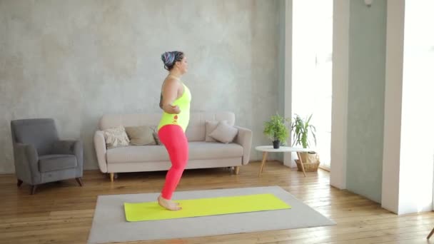 Gros femme en sportswear lumineux saute la corde en faisant du cardio à la maison, vue de côté. — Video