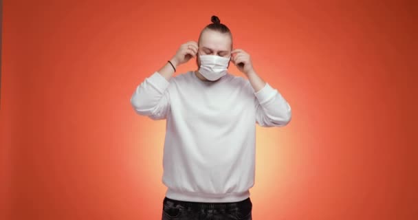 Homem barbudo tira máscara médica e faz respiração profunda no fundo vermelho. — Vídeo de Stock