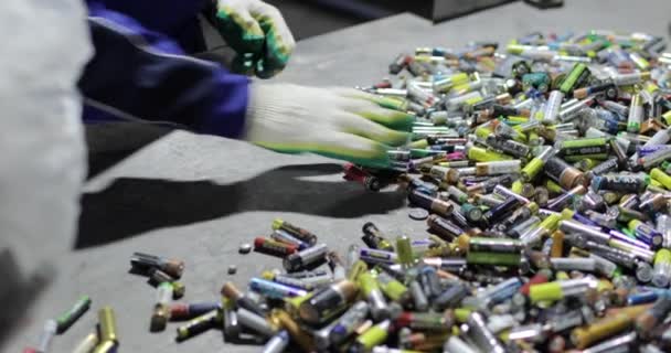Utsikt över händerna på en person i handskar sortera begagnade batterier. — Stockvideo