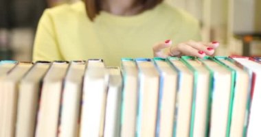 Genç kadın okumak için bir kitap seçiyor. Yakın plan..