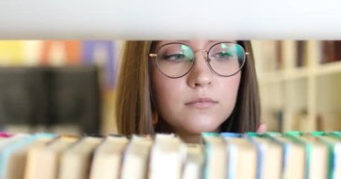 Kitap seçen gözlüklü güzel Avrupalı kız öğrenci. Yakın plan..