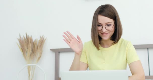 Joven hermosa mujer se está comunicando, sentado en la cama delante de un ordenador portátil. Primer plano. — Vídeos de Stock