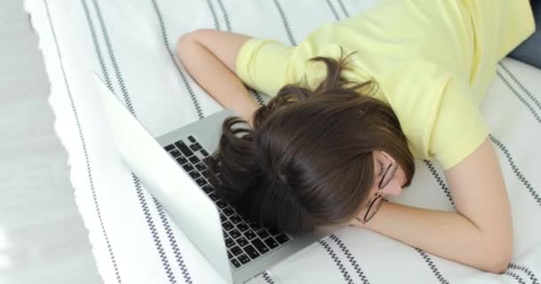 Ung vacker kvinna somnade på sängen, hennes huvud är på laptop tangentbordet. Ovanifrån. — Stockvideo