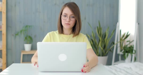 年轻漂亮的女人正坐在笔记本电脑前的桌子上。前景. — 图库视频影像