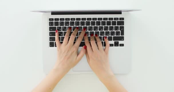 Manos con esmalte de uñas rojo de mujer joven presionando las teclas del ordenador portátil. Vista superior. — Vídeo de stock