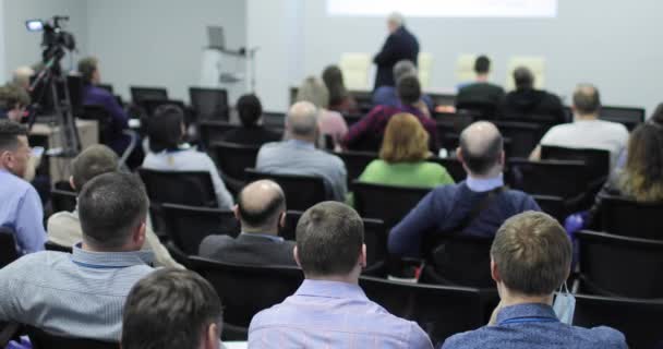 The audience is listening to the lecturer in the conference room. Back view. — Stock Video