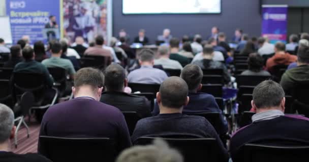 Publikum poslouchá přednášejícího v konferenčním sále. Připravuje prezentaci. Zadní pohled. — Stock video