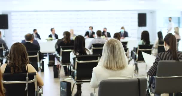 Mensen zitten op stoelen op de conferentie en luisteren naar de docent. Achteraanzicht. — Stockvideo