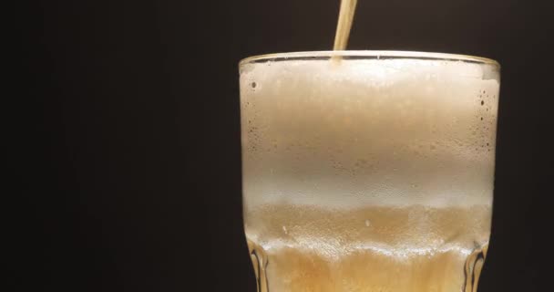 La birra viene versata in un bicchiere. Si forma schiuma. Primo piano. — Video Stock