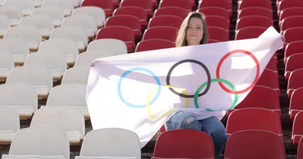ТОКИО, Япония - 21 июля 2021 года: женщина с олимпийским флагом, болеющая за спортсменов на Олимпийских играх, стоит на пустом подиуме — стоковое видео