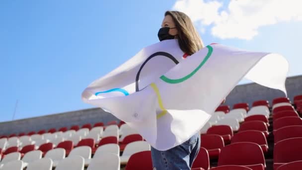 TOKYO, JAPONYAN - 21 Temmuz 2021 Olimpiyat oyunlarında olimpiyat bayrağı taşıyan koruyucu maskeli bir kadın boş bir podyumda ayakta duruyor. — Stok video