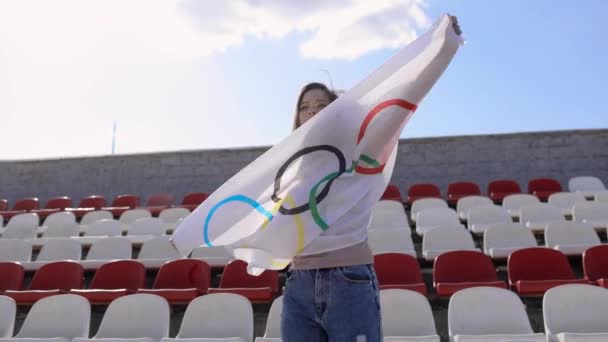 TOKYO, JAPONYAN - 21 Temmuz 2021 Olimpiyat oyunlarında olimpiyat bayrağı taşıyan koruyucu maskeli bir kadın boş bir podyumda ayakta duruyor. — Stok video