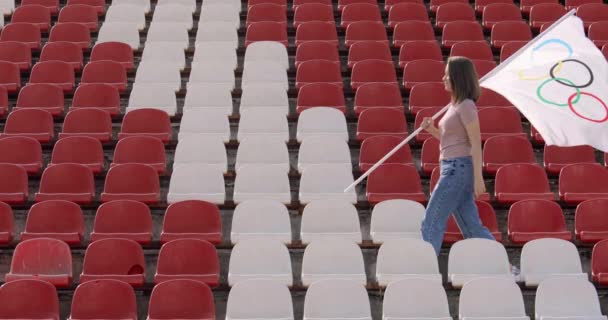 TOKYO, JAPAN - JULY 21, 2021: a woman walks down an empty podium and carries an olympic flag — Stockvideo