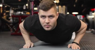 Genç sporcu spor salonunda şınav çekiyor. Sporcu fitness ile meşgul. Ön görünüm.