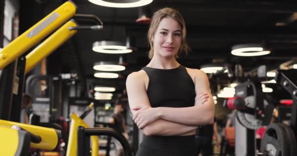 Siyah bir konu takan güzel bir atletik kadının portresi, gülümsüyor, spor salonundaki güç antrenmanından sonra dinleniyor. Ön görünüm. — Stok video