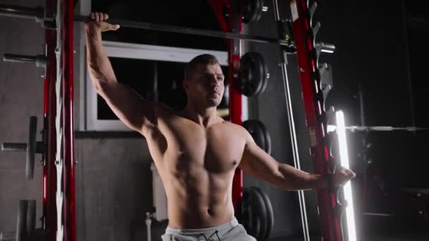 Портрет спортивного юноши, занимающегося в спортзале силовыми упражнениями, толкающего штангу одной рукой. — стоковое видео