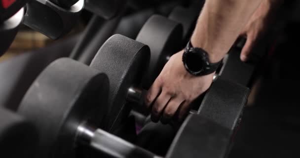 Mužská ruka s chytrými hodinkami, která si v tělocvičně bere činku. Detailní záběr. — Stock video