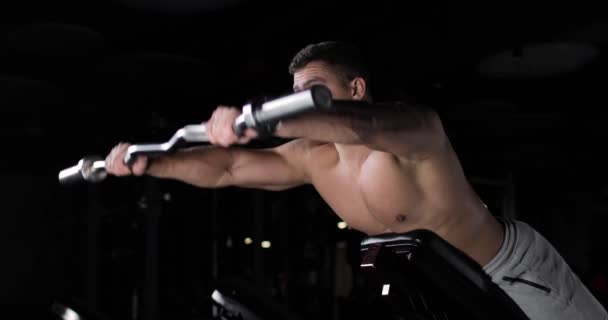 Sportos fiatalember edzés a tornateremben egy karosszéria, fekvő csinál gyakorlatokat az izmok a hát, bicepsz, váll. — Stock videók