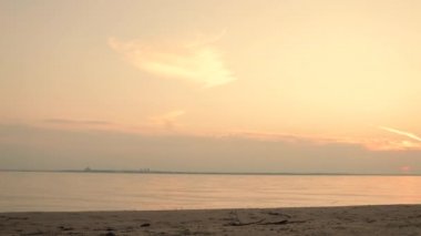 Güzel gün doğumu ya da gün batımı. Nehir kıyısı boyunca koşan beyaz şortlu atletik genç adam. Yavaş çekim.