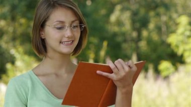 Young woman reading book with orange cover
