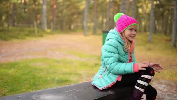 Niña sonriente con chaqueta azul en el parque de otoño — Vídeo de stock