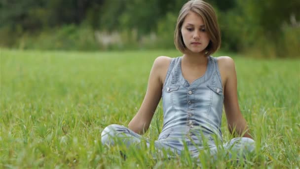 年轻女子坐在草 — 图库视频影像