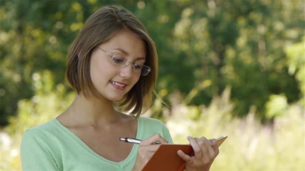 Chica hace una entrada en el cuaderno — Vídeo de stock