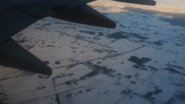 Avión vuela sobre campos cubiertos de nieve — Vídeos de Stock