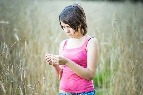 Young female stands in crop field holding flower — Stock Photo, Image