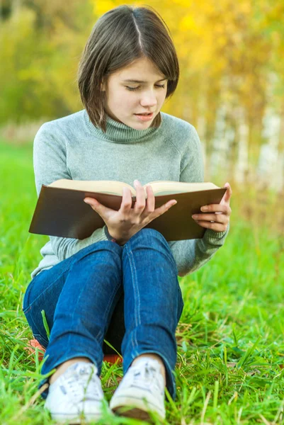 Joven hermosa chica se sienta en el puente y lee libro — Foto de Stock