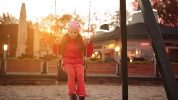 Menina bonita em um balanço no parque da cidade de outono . — Vídeo de Stock