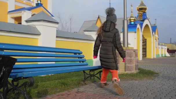 Mooi meisje zittend op een bankje op een stad straat. — Stockvideo