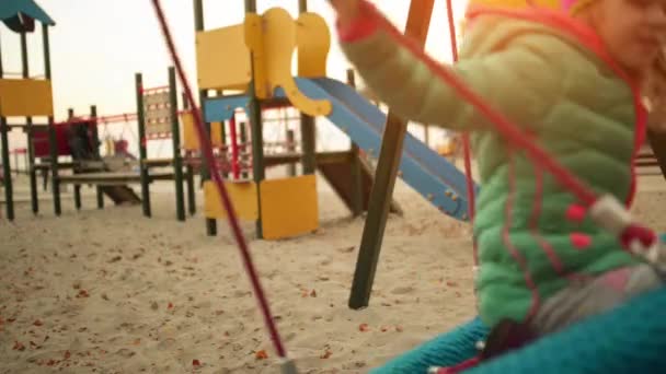 Hermosa niña en un columpio en el parque de otoño de la ciudad . — Vídeo de stock