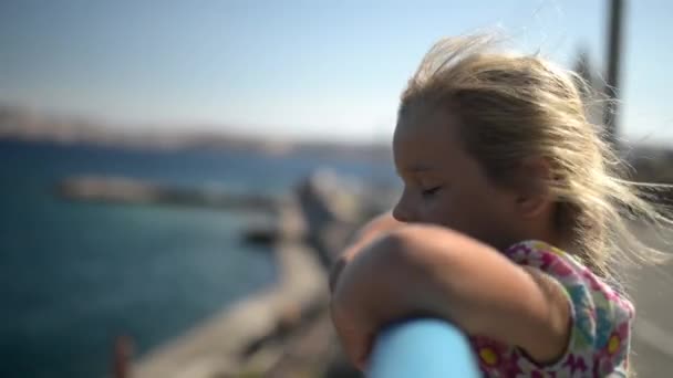 Lilla leende vackra flickan står nära räcket vid Adriatiska kusten i Kroatien. — Stockvideo