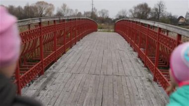 İki güzel kızın sonbahar Şehir Parkı gölette köprüden yürü.