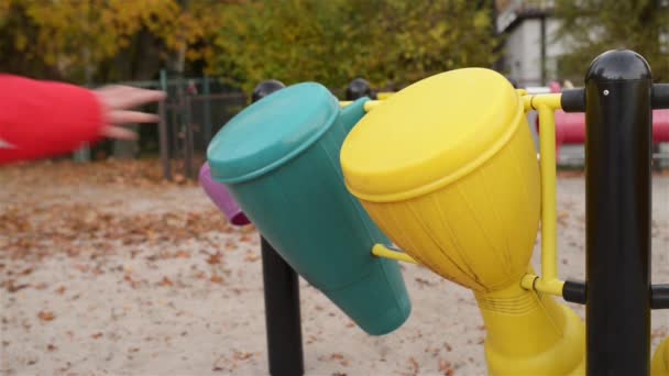 Kleines Mädchen klopft auf Spielzeugtrommel auf dem Spielplatz im Herbst-Stadtpark. — Stockvideo