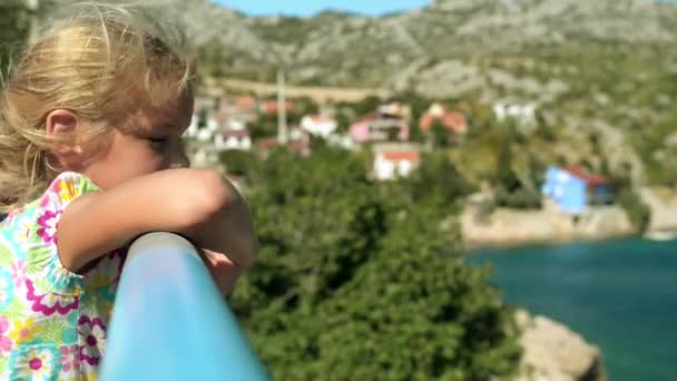 Pequena menina bonita sorridente de pé perto do corrimão na costa do Adriático na Croácia . — Vídeo de Stock