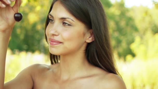 Close-up retrato de jovem atraente rindo mulher comendo cerejas doces no verão parque verde . — Vídeo de Stock