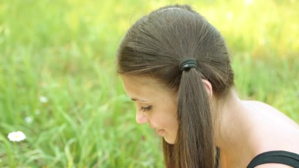 Portret van jonge aantrekkelijke lachende vrouw dragen zwarte blouse zit zomer groen gras. — Stockvideo