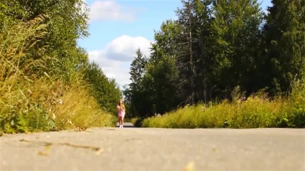 Mooie jonge vrouw wordt uitgevoerd op de weg in het groene zomer park. — Stockvideo