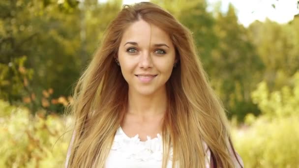 Retrato de una hermosa joven sonriente, contra el verde del parque de verano . — Vídeos de Stock