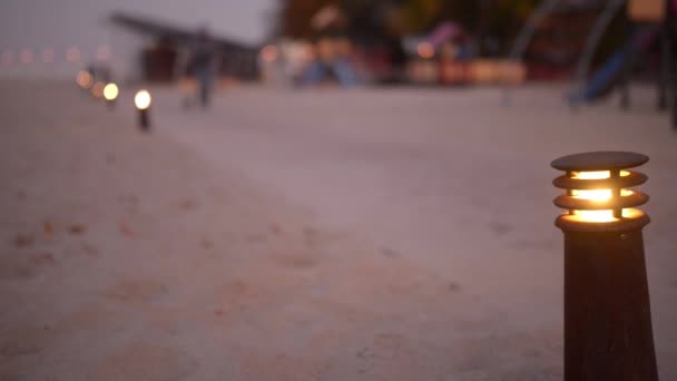 Angezündete Laterne auf dem Hintergrund von Menschen, die im abendlichen Herbstpark spazieren gehen. — Stockvideo