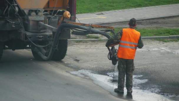 4 k stavební dělník oprava díry na silnici s štěrku a asfalt s pomocí speciálního vybavení. — Stock video