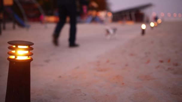 Angezündete Laterne auf dem Hintergrund von Menschen, die im abendlichen Herbstpark spazieren gehen. — Stockvideo