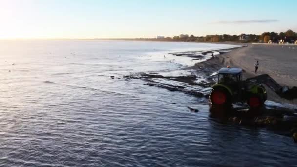 SOPOT, POLAND - OCTOBER 24 2015: Tractor removes algae and debris on coast of Baltic Sea around pier in Sopot. Sopot (Zoppot) is a seaside resort town in Eastern Pomerania in northern Poland. — Stock Video