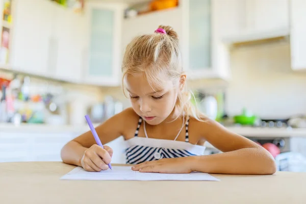 Liten flicka skriver med penna i anteckningsboken — Stockfoto