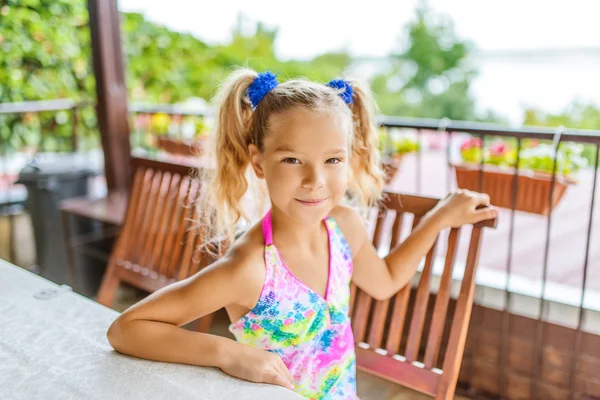 Kleines Mädchen mit Zöpfen sitzt in Pavillon — Stockfoto