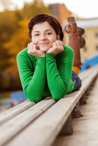 Jolie jeune femme allongée sur un banc — Photo