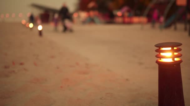 Angezündete Laterne auf dem Hintergrund von Menschen, die im abendlichen Herbstpark spazieren gehen. — Stockvideo
