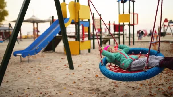 Hermosa niña en un columpio en el parque de otoño de la ciudad . — Vídeos de Stock